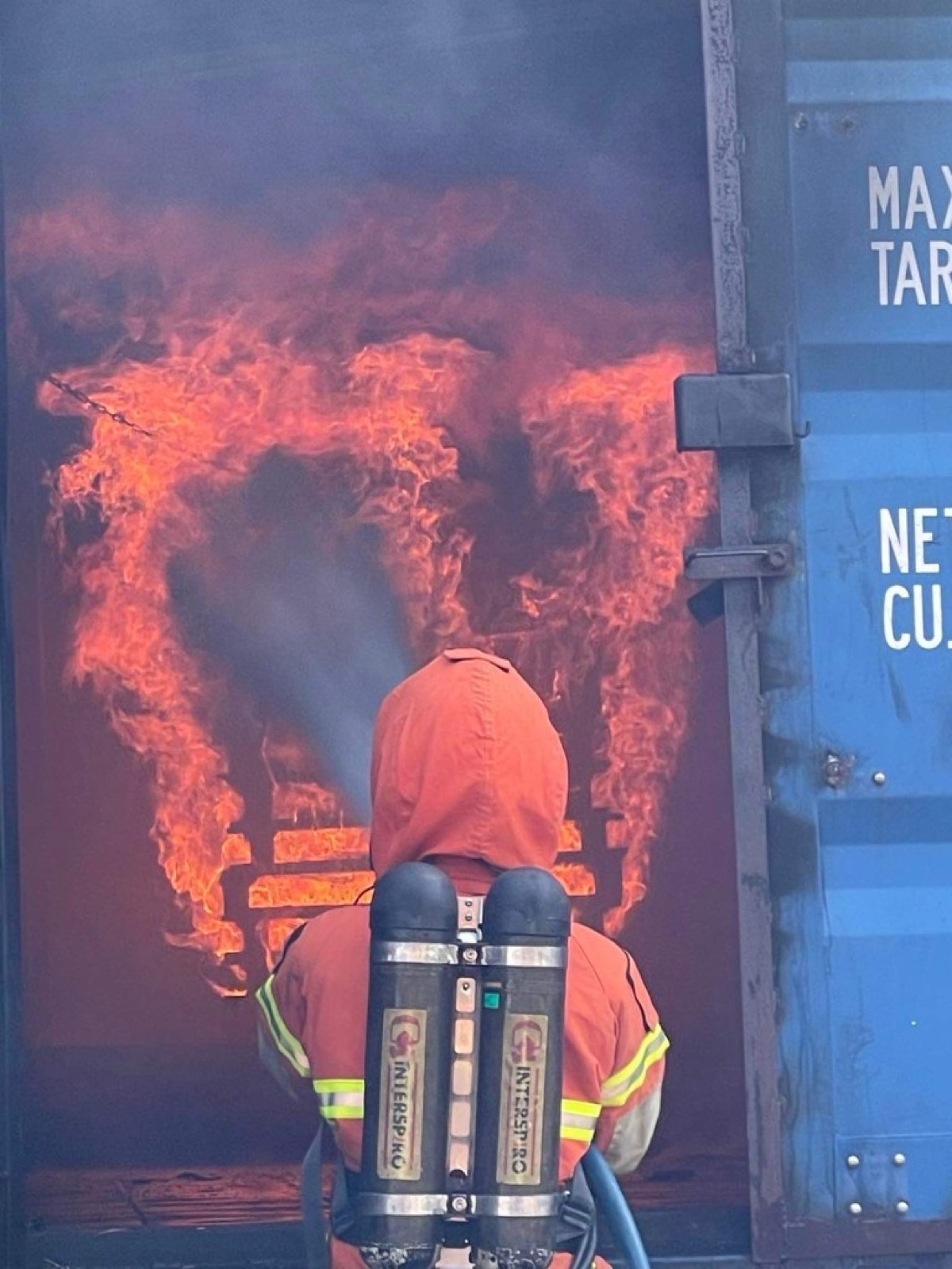 Jacob in full firefighter gear fighting a live fire in a training container
